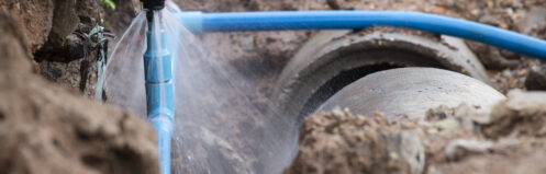 Burst water main with water spraying in a hole in the ground