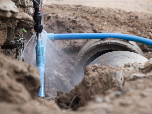 Burst water main with water spraying in a hole in the ground