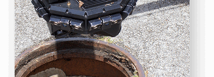 Sewer hole in the ground open with a camera set aside of the hole ready to be used